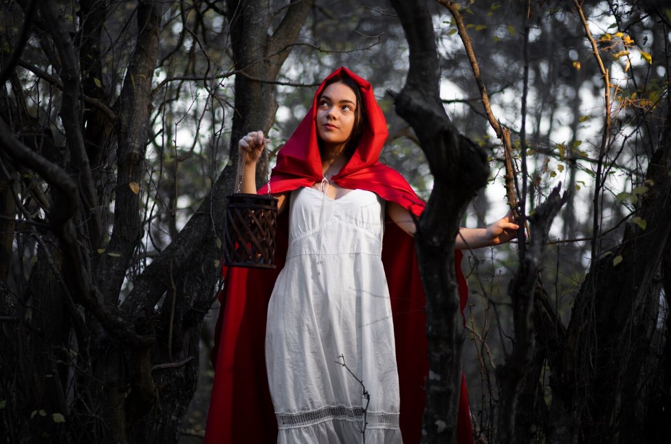 Little Red Riding Hood walking through the forest in a white dress