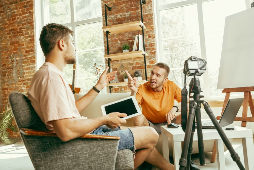 two young men in casual clothes talk in room with with professional equipment